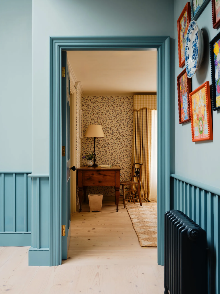 Couloir avec boiseries et encadrements de portes peints en bleu dans une maison élégante.